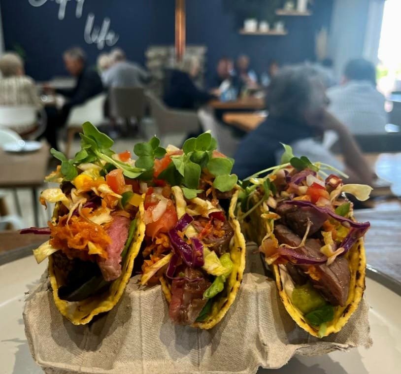 Three steak tacos with slaw and salsa, served in an egg-box holder